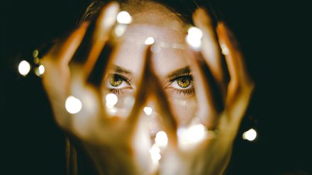 Regard intense d'une femme tenant des lumières dans ses mains et devant son visage