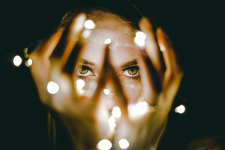 Regard intense d'une femme tenant des lumières dans ses mains et devant son visage