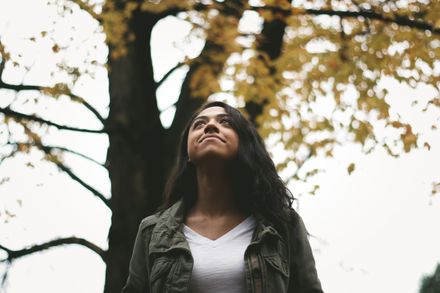 Femme métisse levant les yeux au ciel sur fond d'arbre