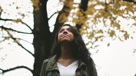 Femme métisse levant les yeux au ciel sur fond d'arbre