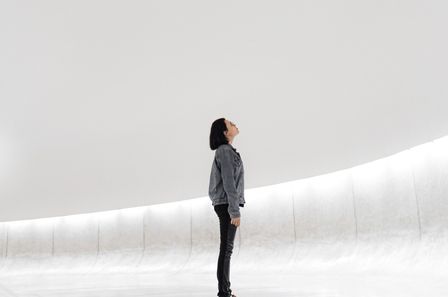 Jeune femme à lunettes dans un espace vide et blanc regardant vers le haut