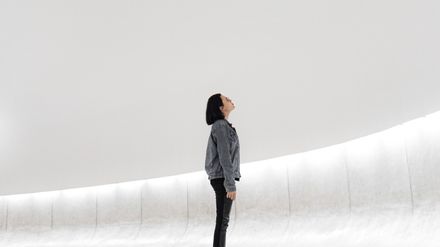 Jeune femme à lunettes dans un espace vide et blanc regardant vers le haut