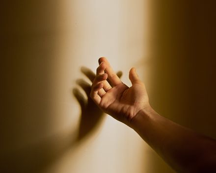 Main masculine ouverte projettant son ombre contre un mur ensoleillé sur lequel est est posée