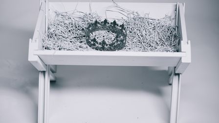 Mangeoir à foin blanche contenant une couronne en argent
