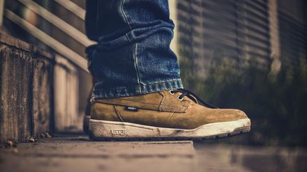 Personne se tenant sur une marche d'escalier, de profil, dont on ne voit qu'une paire de chaussures de marche brunes
