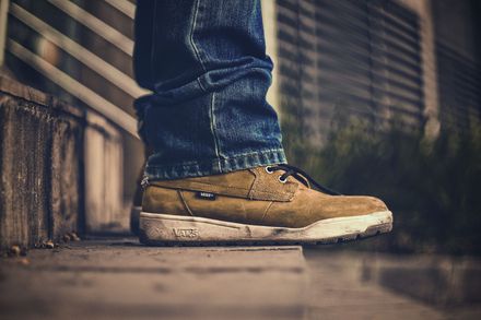 Personne se tenant sur une marche d'escalier, de profil, dont on ne voit qu'une paire de chaussures de marche brunes