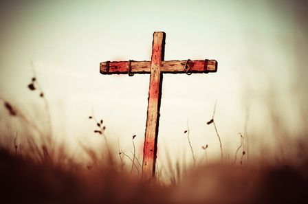 Croix en bois vide avec des traces de sang dans un champ d'herbes hautes