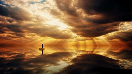 Une personne dans une barque sur une étendue d'eau lisse reflétant parfaitement un ciel lumineux jaune orangé