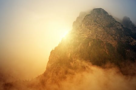 Montagne arborée et embrumée brillante de la lumière dorée diffuse du soleil