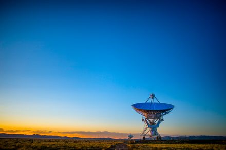 Grande antenne satellite pointée vers un ciel de lever de soleil