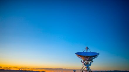 Grande antenne satellite pointée vers un ciel de lever de soleil