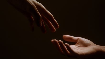 Main tendue vers une autre dans une ambiance lumineuse tamisée