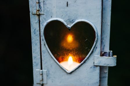 Lampe ancienne dont la vitre est en forme de coeur à l'intérieur de laquelle brûle une bougie