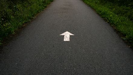 Flèche blanche peinte sur une route.