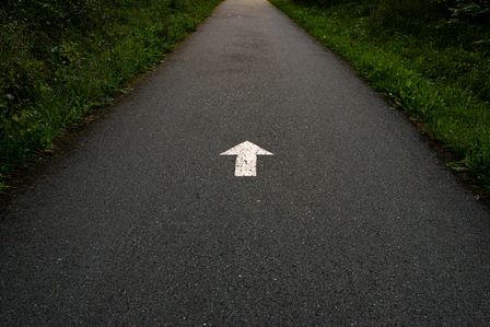 Flèche blanche peinte sur une route.