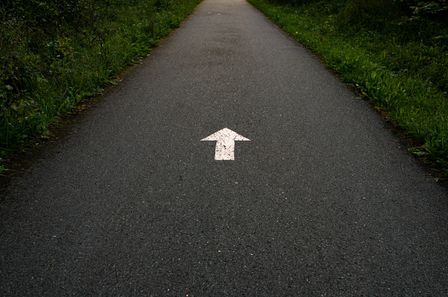 Flèche blanche peinte sur une route.