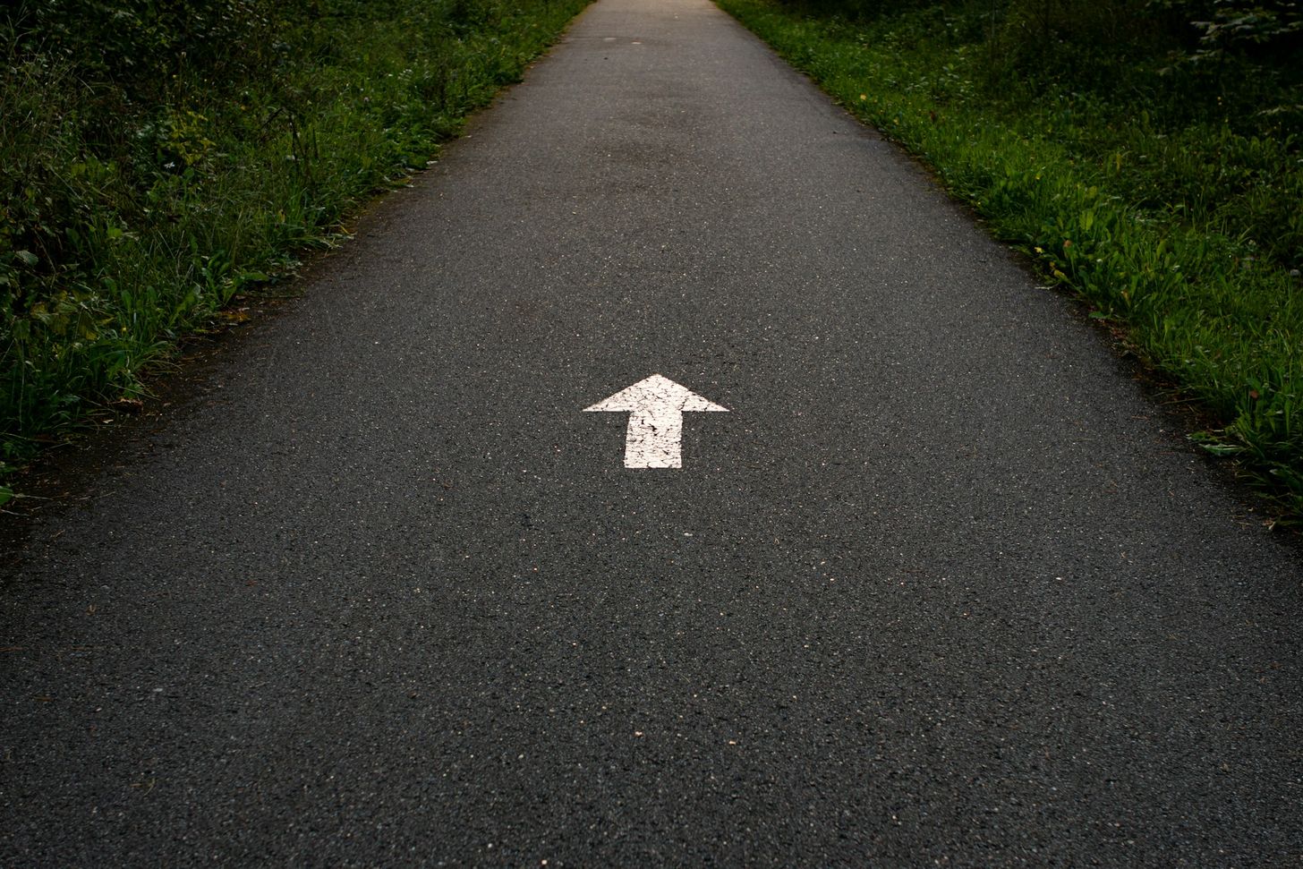 Flèche blanche peinte sur une route.