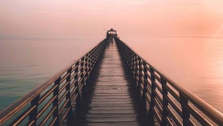 Ponton en bois sur l'océan sur un lever de soleil bleu et rose