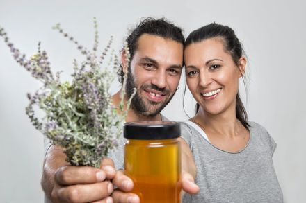 Couple souriant et montrant un pot de miel et un bouquet de lavande