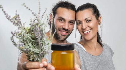 Couple souriant et montrant un pot de miel et un bouquet de lavande