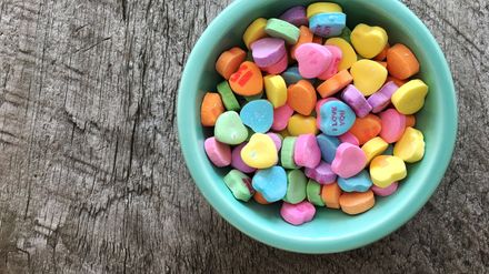 Bol vert pastel contenant des bonbons multicolores en forme de coeur