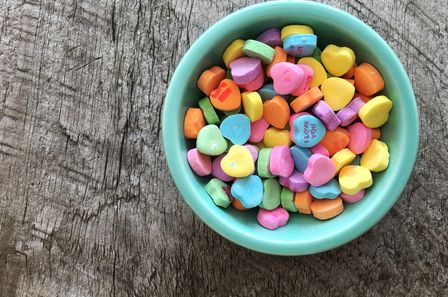 Bol vert pastel contenant des bonbons multicolores en forme de coeur