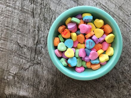 Bol vert pastel contenant des bonbons multicolores en forme de coeur