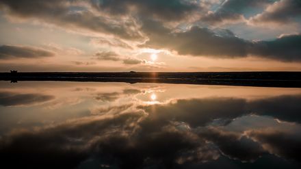 Lever de soleil sur une étendue d'eau donnant un effet miroir