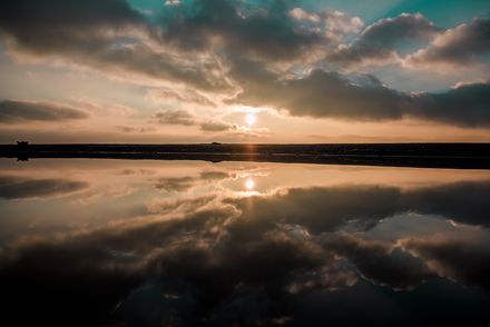 Lever de soleil sur une étendue d'eau donnant un effet miroir