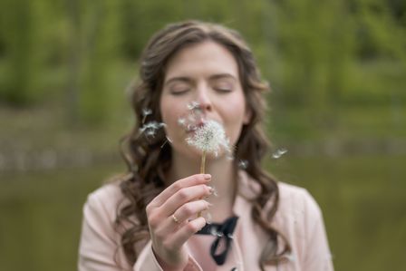 Femme soufflant une fleur de pissenlit
